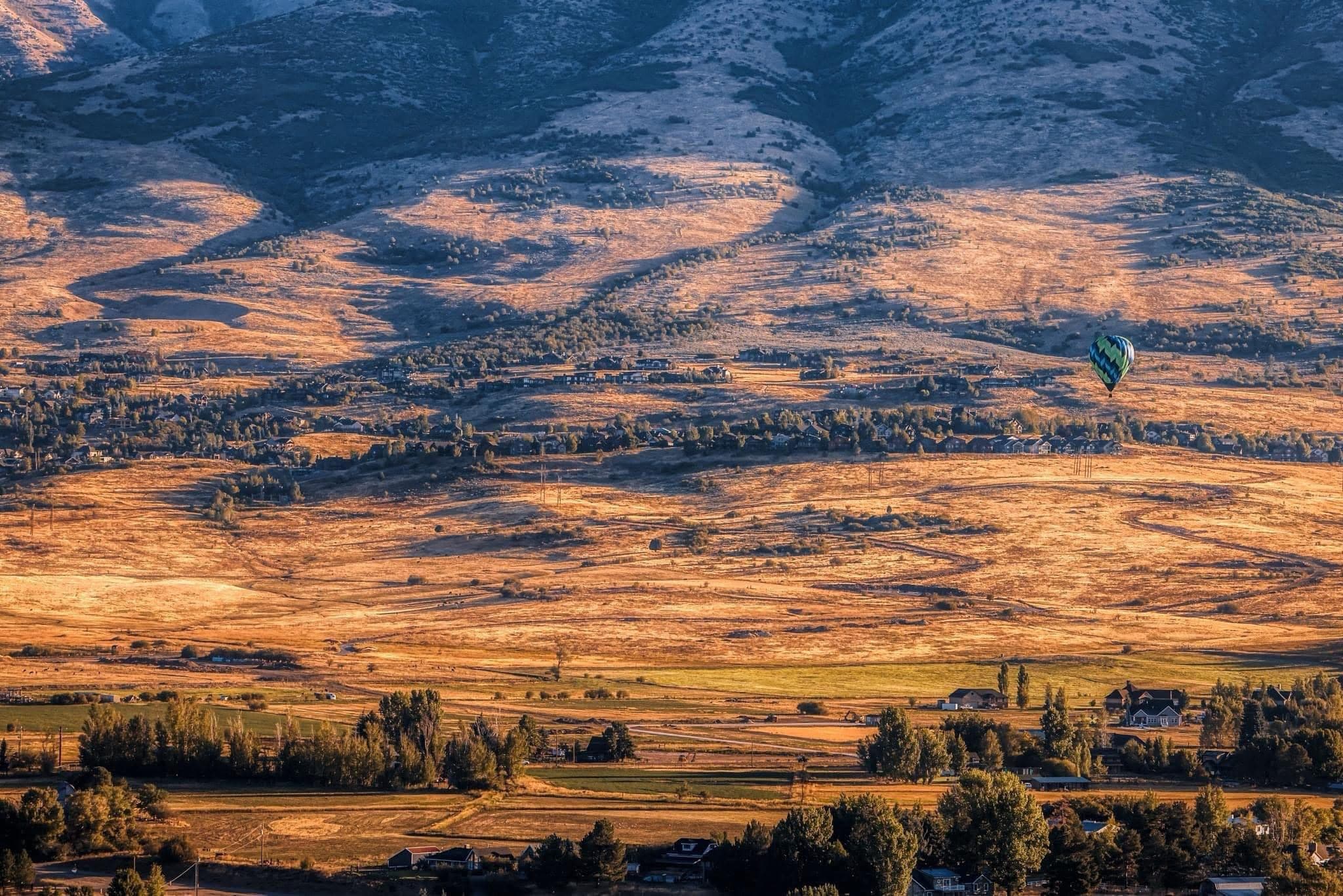 Hot air balloon floating over Utah mountains at sunrise